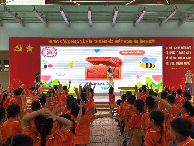 A group of children in orange shirts raising their hands

Description automatically generated